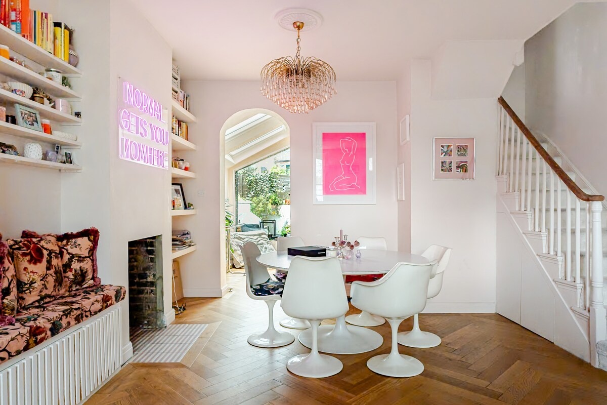 Dining room with tulip table and chairs, pink neon sign and hot pink line-drawing artwork
