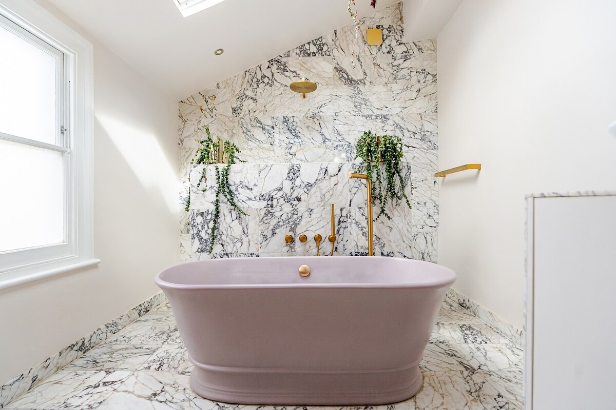 Freestanding blush pink bateau bath on a marble floor